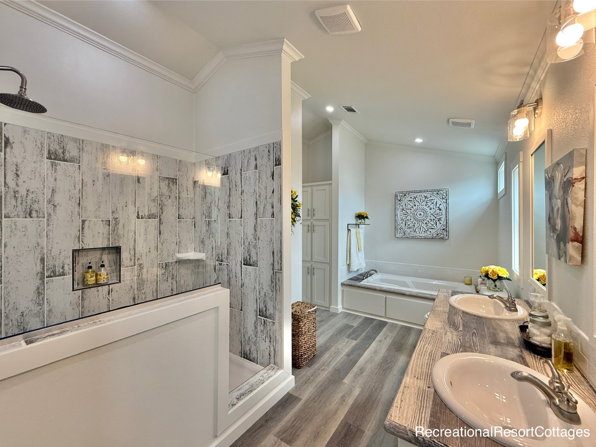 Luxurious bathroom with a dual-sink wooden vanity, large bathtub, and a spacious walk-in shower with rustic tile. Soft lighting and decor add elegance.