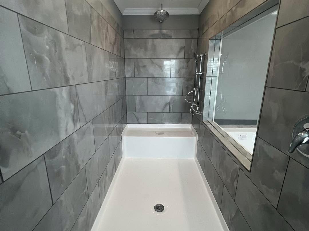 Modern bathroom shower with sleek gray marble tiles and a large window. The clean design and chrome fixtures create a minimalist, elegant feel.