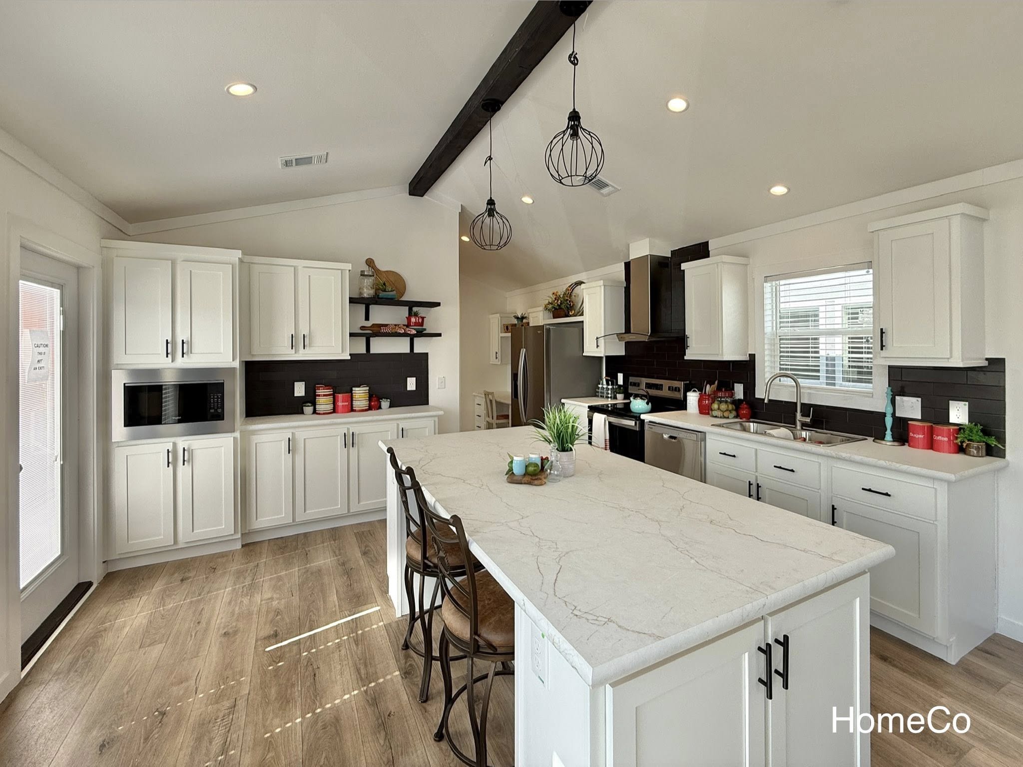 Luxury manufactured home tour featuring the expansive "The Boujee XL" 4-to-5 bedroom floor plan, showcasing a blend of modern farmhouse and industrial chic aesthetics. Exterior designs include a sleek white double-wide with charcoal accents and a light grey board-and-batten park model featuring a grand pillared front porch. Interior highlights feature massive open-concept living areas with integrated electric fireplaces, grey shiplap accent walls, and rustic wood ceiling beams. Gourmet kitchens are equipped with oversized charcoal or white islands featuring "X" brace detailing, marble-look countertops, and premium stainless steel appliances. Spa-inspired primary bathrooms boast walk-in tile showers with black matte trim, freestanding soaking tubs, and double vanities with LED-mirrored lighting. Additional features include a primary suite with a bold black accent wall and cowhide rug, a custom laundry utility room, and a versatile layout perfect for large families.