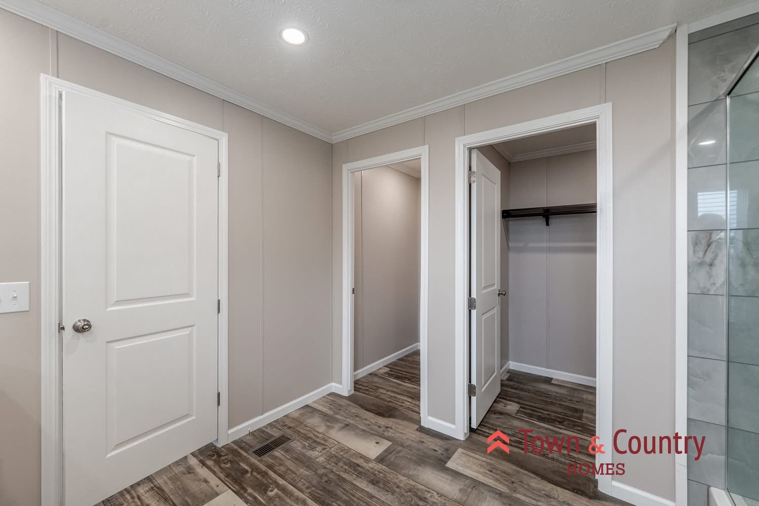 Bright, beige hallway with wooden floors, three white doors. One door open to an empty closet. Modern and minimal design with a calm tone.