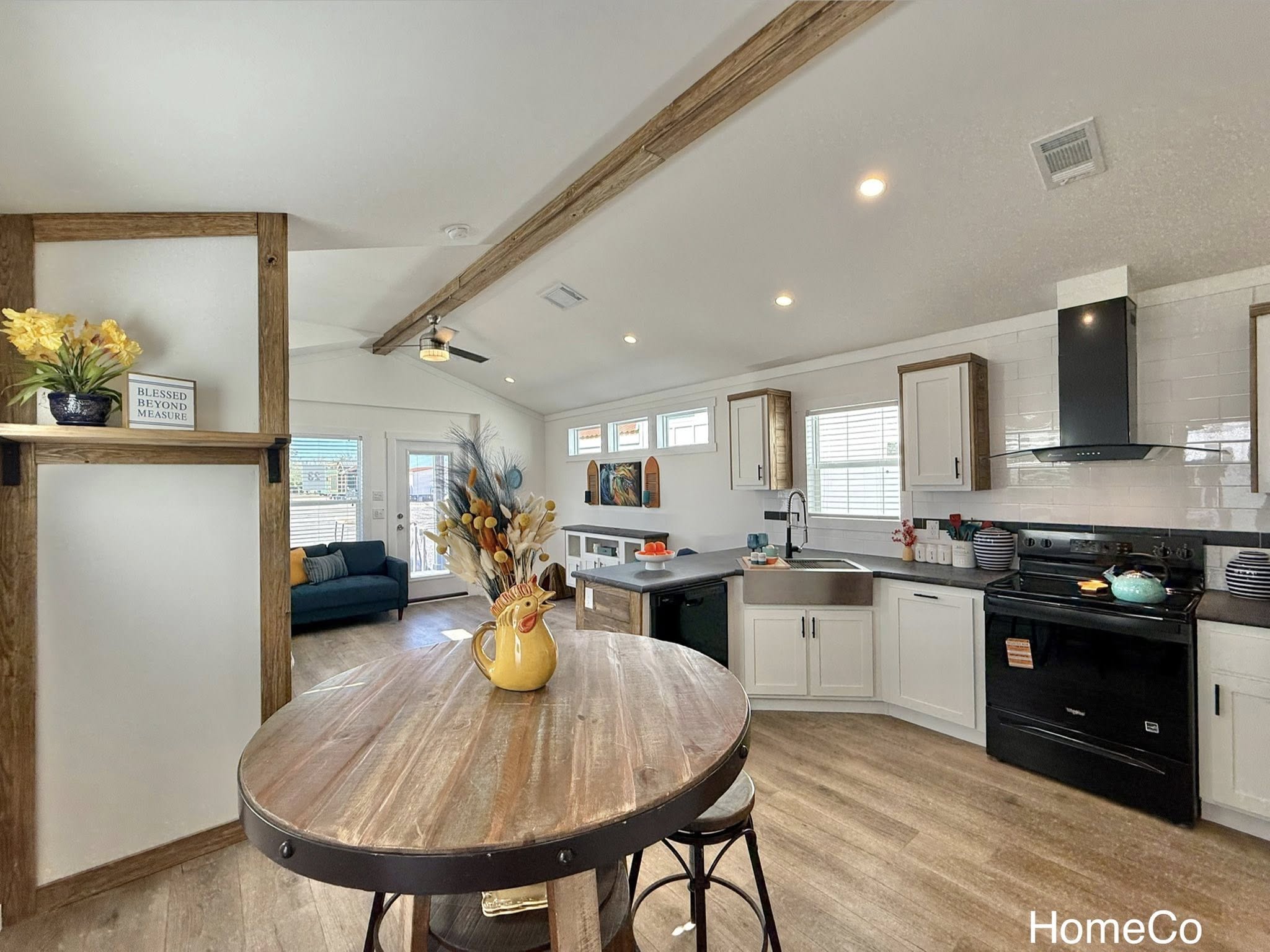 Luxury modular farmhouse and modern tiny home collection featuring navy blue exteriors, gourmet white kitchens with quartz waterfall islands, hidden arched pantries, and open-concept interiors with vaulted ceilings, stone fireplaces, and geometric green accent walls.