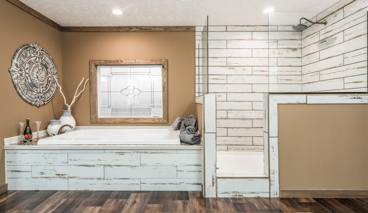 Rustic bathroom with wood accents. Features a whitewashed tub and shower, brown walls, decorative wall art, and a stained glass window. Cozy and serene ambiance.