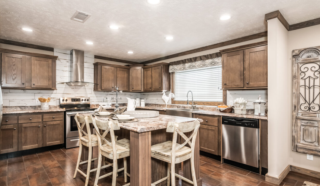 Spacious kitchen with rustic wood cabinets and island, surrounded by four wooden chairs. Stainless steel appliances and under-cabinet lights create a warm ambiance.