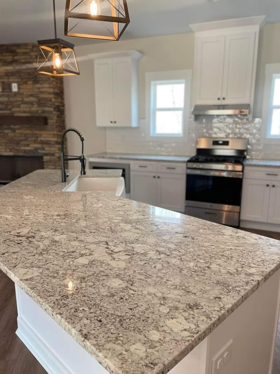 Modern kitchen with granite countertops, white cabinets, stainless steel stove, and farmhouse sink. Pendant lights add warmth and style.