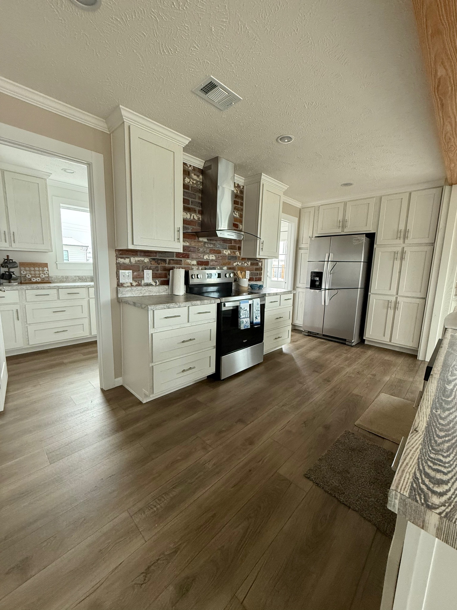 Modern kitchen with white cabinets, stainless steel appliances, and a brick backsplash. Wooden floors add warmth, creating a cozy atmosphere.
