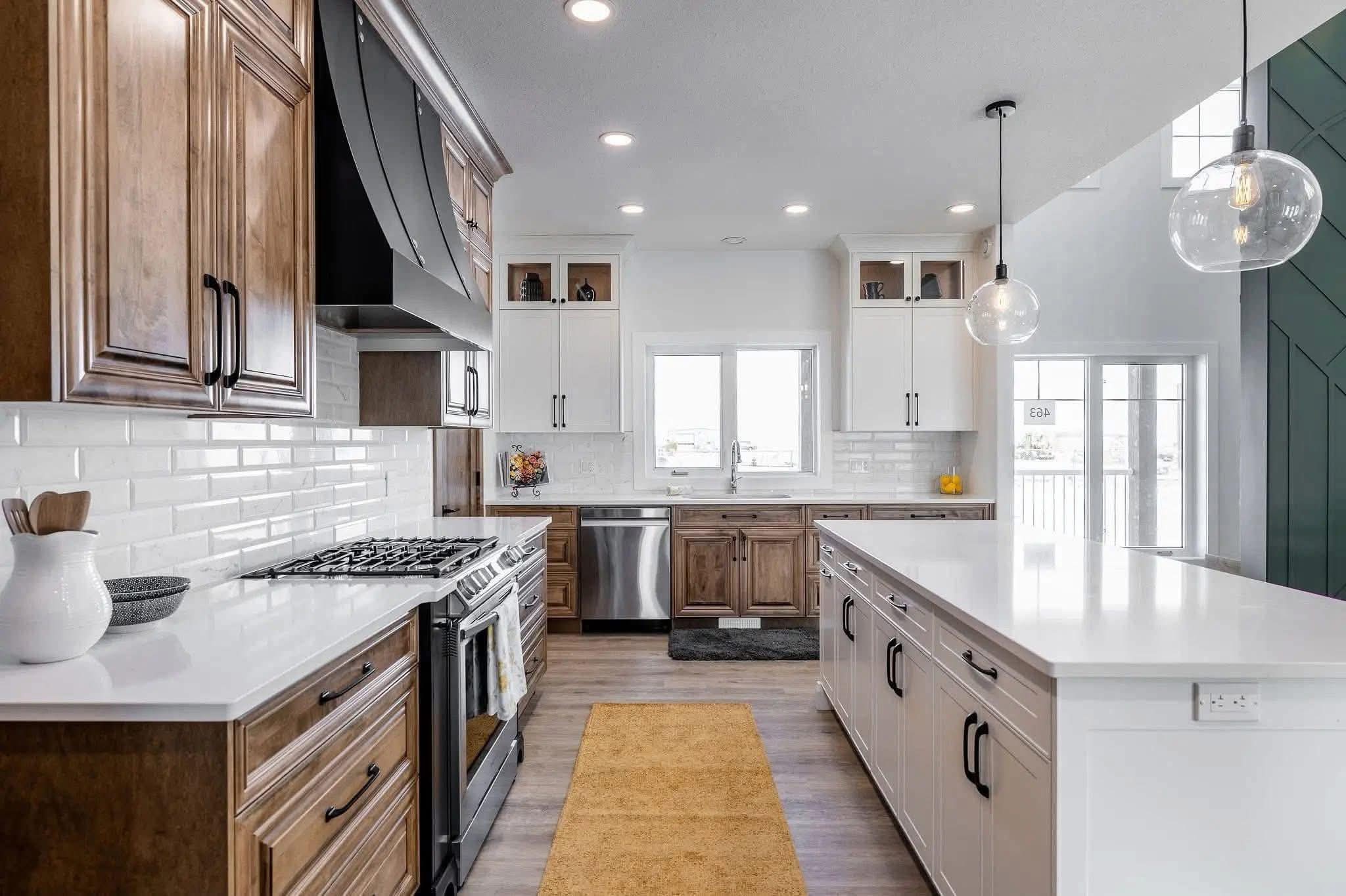 Modern kitchen with wood and white cabinets, a large island, pendant lights, and stainless steel appliances. Bright and spacious with a warm, inviting tone.