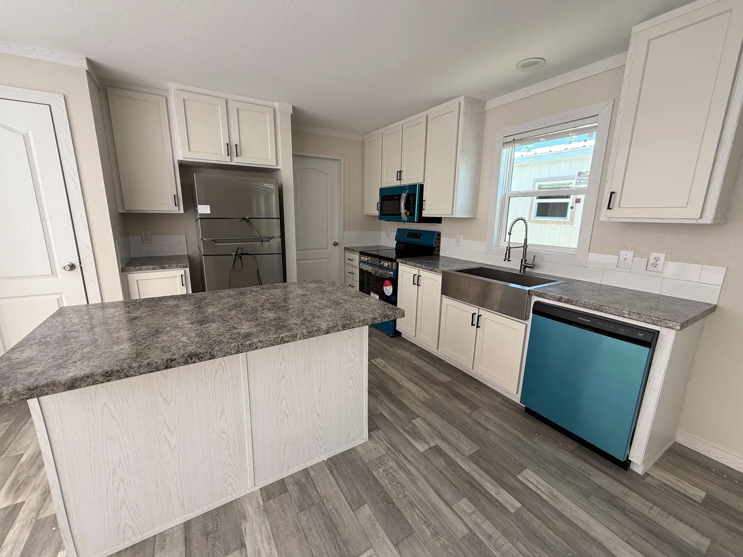 Modern kitchen with light cabinetry, stainless steel appliances, and a gray stone countertop island. The tone is clean and contemporary.