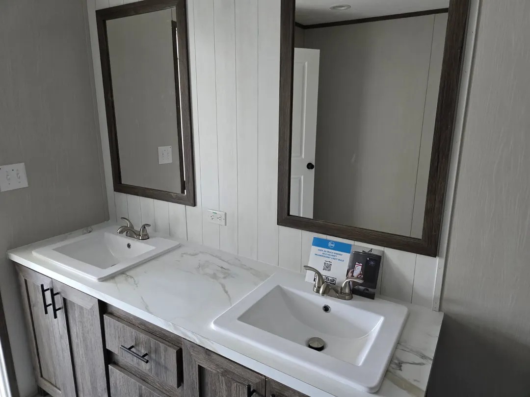 Dual-sink bathroom vanity with marble countertop, dark wooden cabinets, and two large rectangular mirrors. The tone is modern and minimalist.