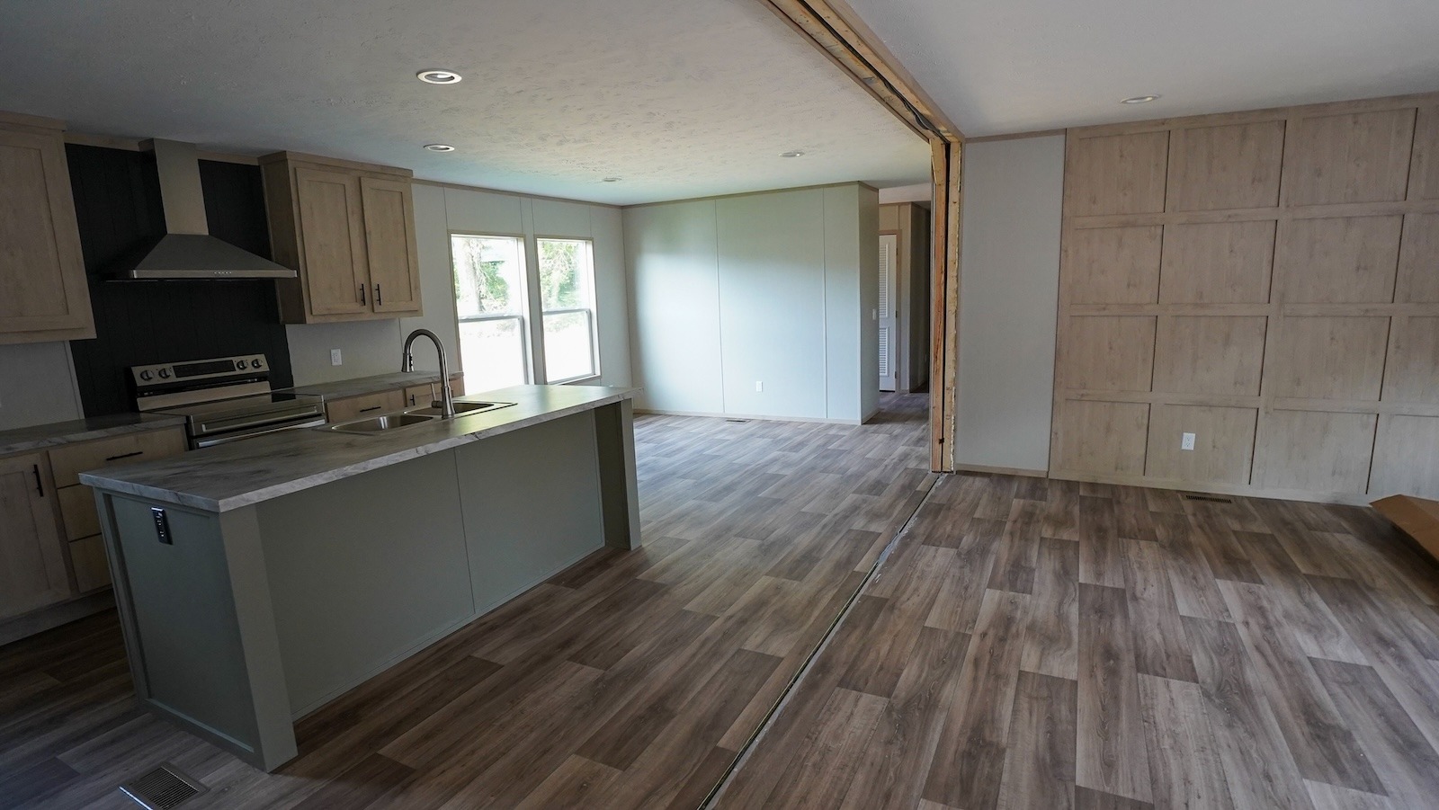 Spacious open-concept kitchen and living area with wooden floors, light wood cabinets, and large windows. Bright, modern, and inviting atmosphere.