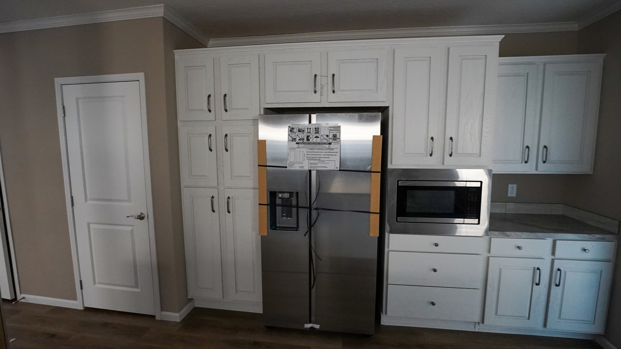 Modern kitchen with white cabinets, a stainless steel refrigerator, and a built-in microwave. Bright, clean, and organized ambiance.