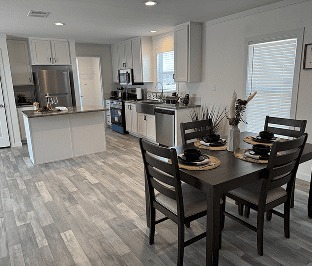 Modern kitchen and dining area with sleek gray flooring. Kitchen includes stainless steel appliances and white cabinets. Dining table is set for four.