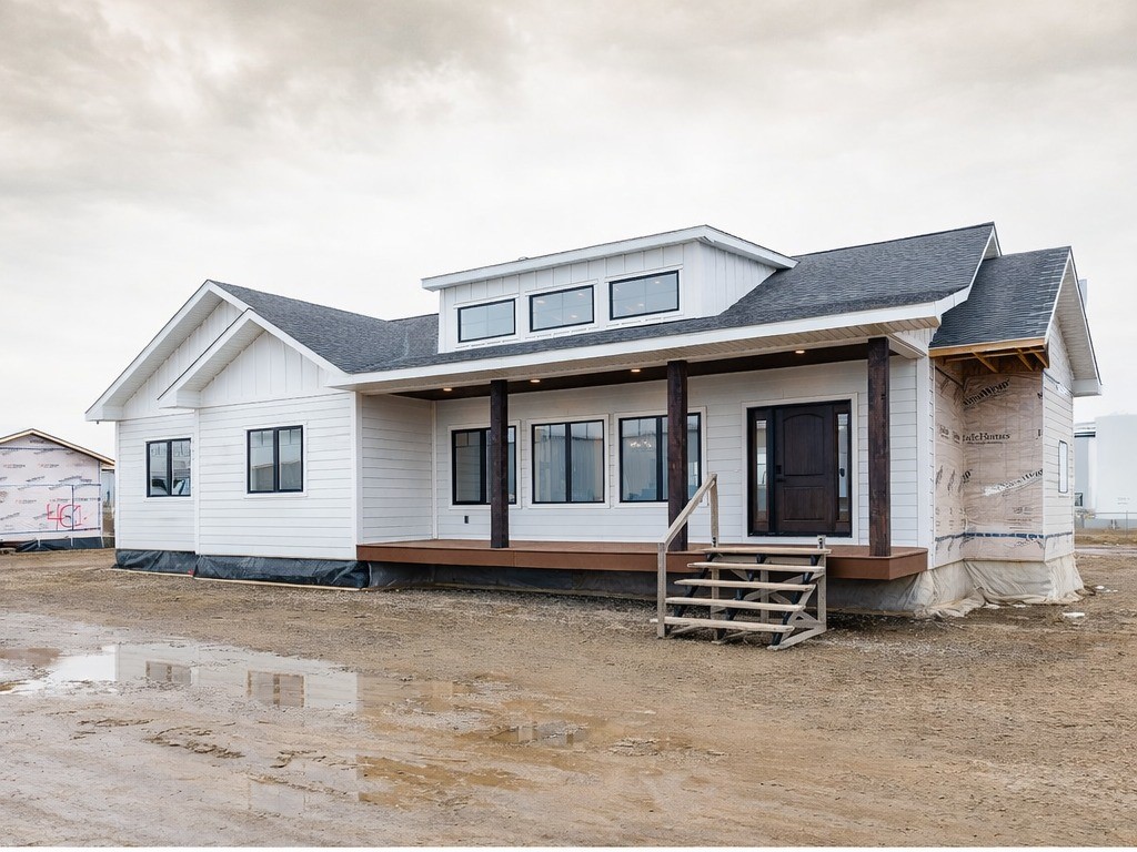 This comprehensive image gallery highlights a variety of luxury housing solutions, including modern farmhouse tiny homes, park models, and large manufactured residences. The exteriors feature high-contrast color palettes, such as white board-and-batten siding paired with dark charcoal gables or full grey siding with natural wood accents. Key architectural details include gabled front porches with substantial support pillars, durable metal or shingle roofing, and large windows that invite natural light.