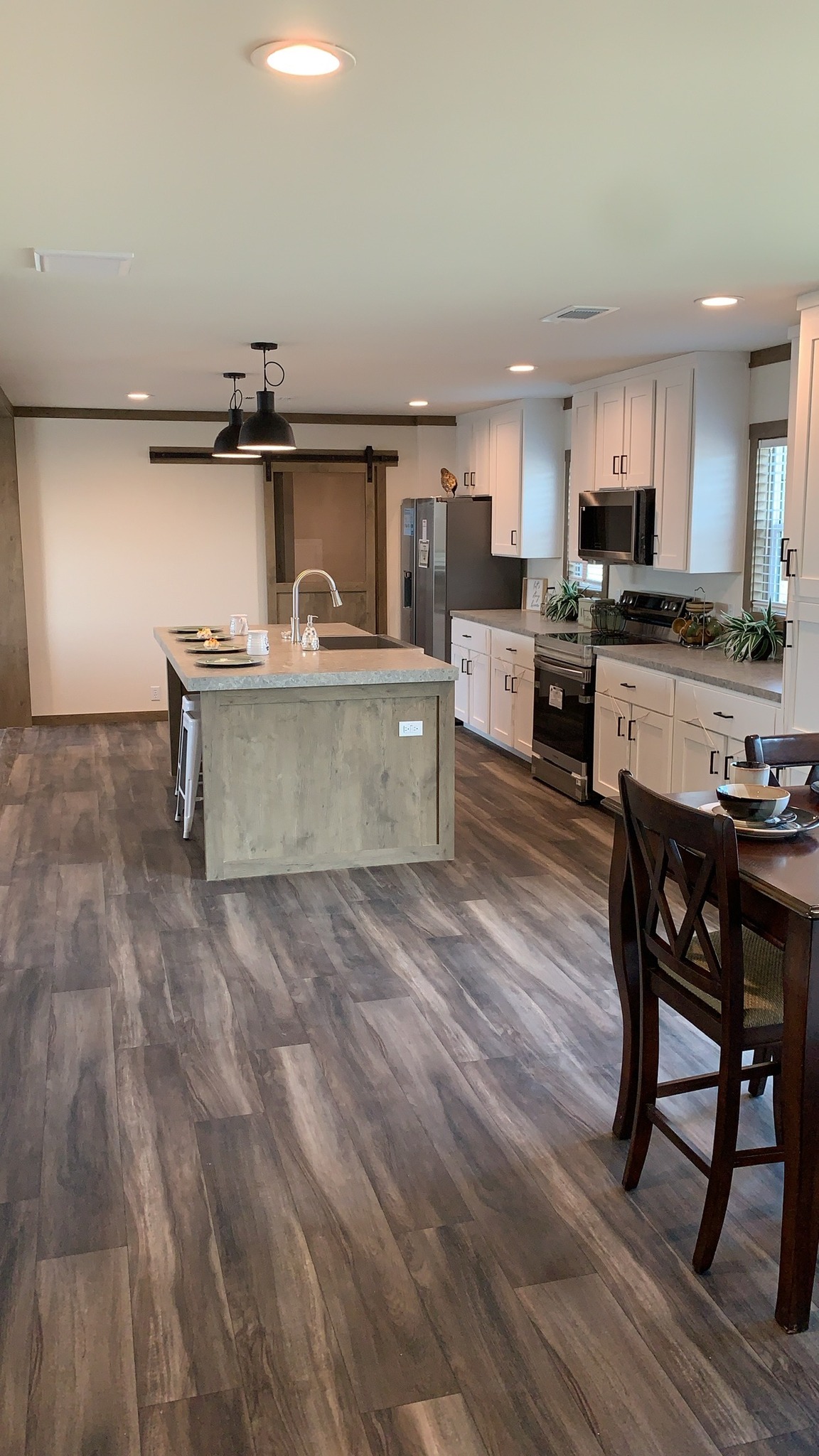 Comprehensive showcase of luxury manufactured and modular homes featuring navy blue and white farmhouse exteriors, 819 SQ FT floor plans, and modern interiors with quartz waterfall islands, hidden arched pantries, industrial corrugated metal accents, stone fireplaces, and vaulted tiny home lofts.