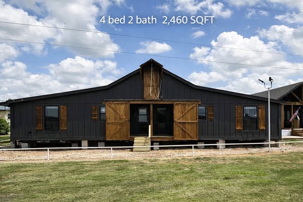 Spacious modern barn-style house with dark siding and rustic wooden shutters, set against a cloudy sky. Features 4 beds, 2 baths, 2,460 sq ft.