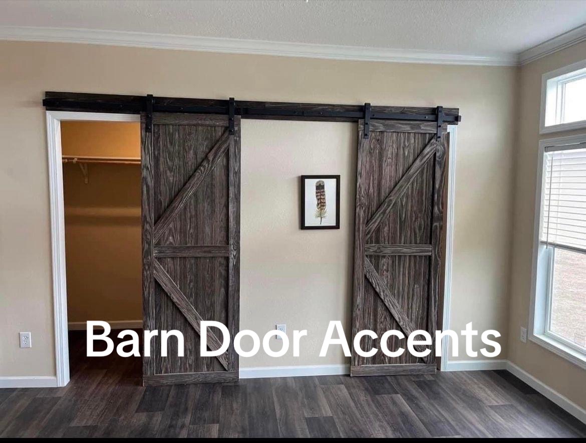 Rustic barn doors on a track frame an open closet against a beige wall. Sunlight filters through large windows, creating a cozy, rustic feel. Text reads "Barn Door Accents."