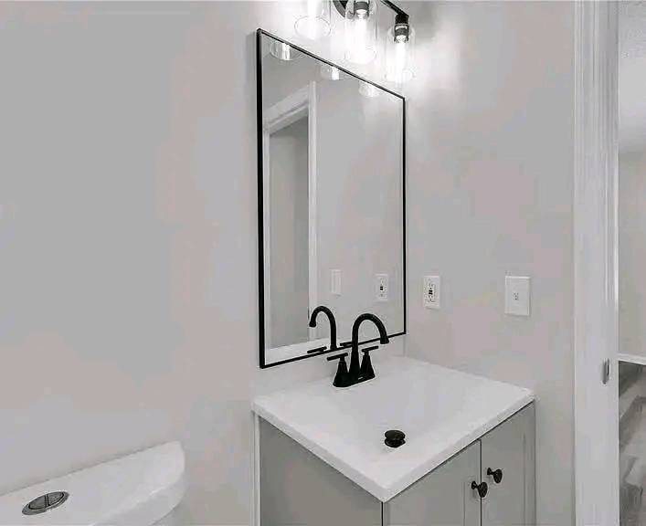 Modern bathroom with a sleek black-framed mirror above a white vanity. The black faucet and minimalistic decor create a clean, contemporary feel.