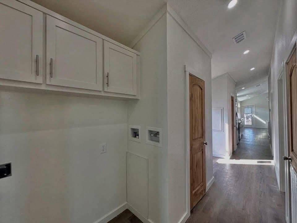 Long, well-lit hallway with white walls, brown wooden doors, and hardwood floors. Upper cabinets on the left add storage space, creating a clean and organized look.