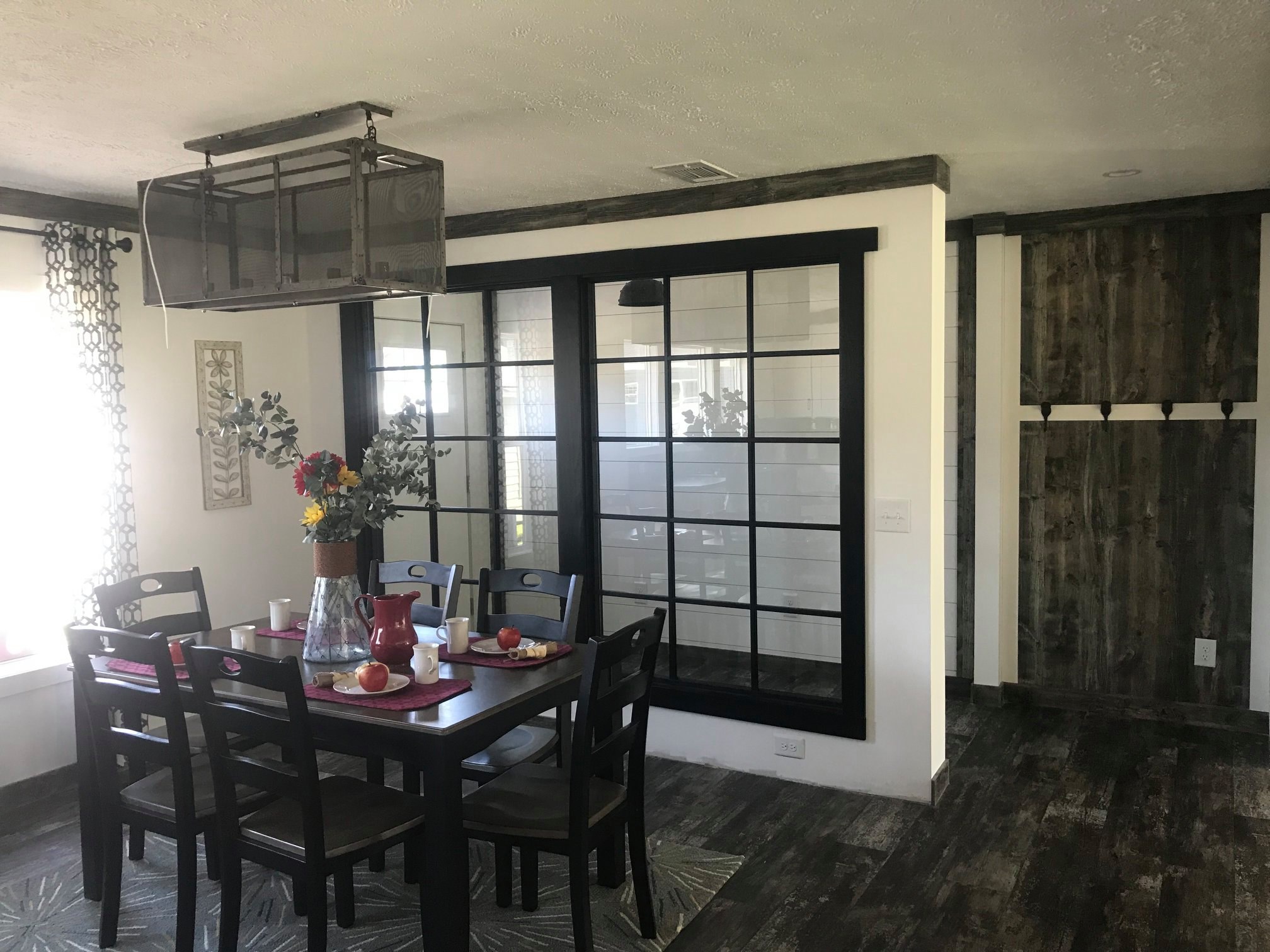Rustic wooden accent wall features four black hooks and an electrical outlet. The wood has a weathered appearance, creating a cozy, farmhouse feel.