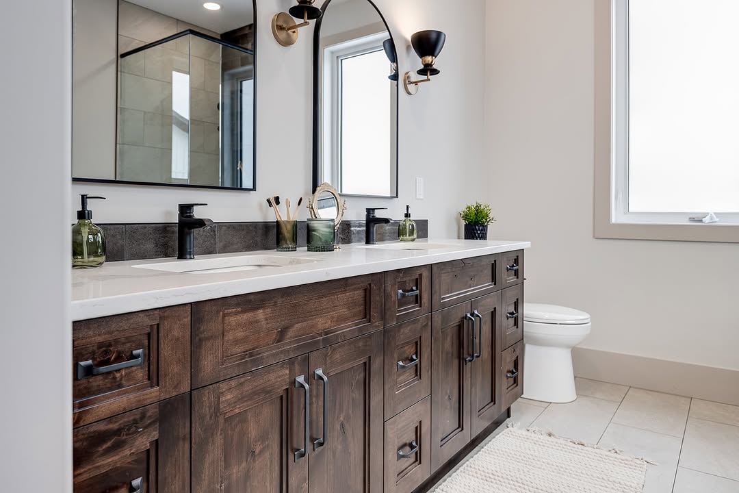 Elegant bathroom with wooden double vanity, black fixtures, and marble countertop. Includes a large mirror, stylish lighting, and a small potted plant.
