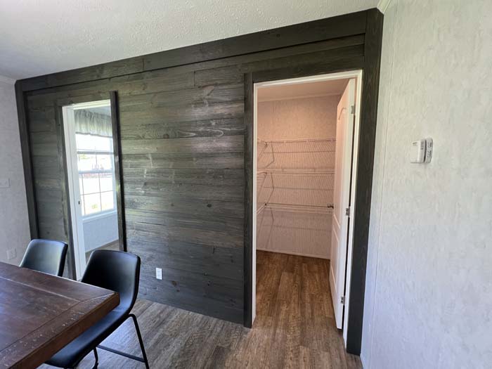 Functional manufactured home storage showing a large walk-in pantry with wire shelving and a decorative dark wood accent wall.