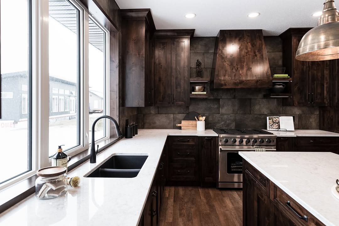 Modern kitchen with dark wood cabinets, stainless steel appliances, and a white marble countertop. A large window provides ample natural light, creating a warm and inviting atmosphere.