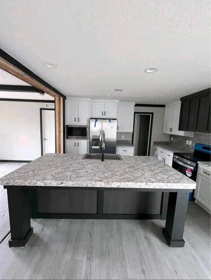Modern kitchen with a large marble island, stainless steel appliances, and white cabinets. The clean lines and neutral tones create a sleek, inviting atmosphere.