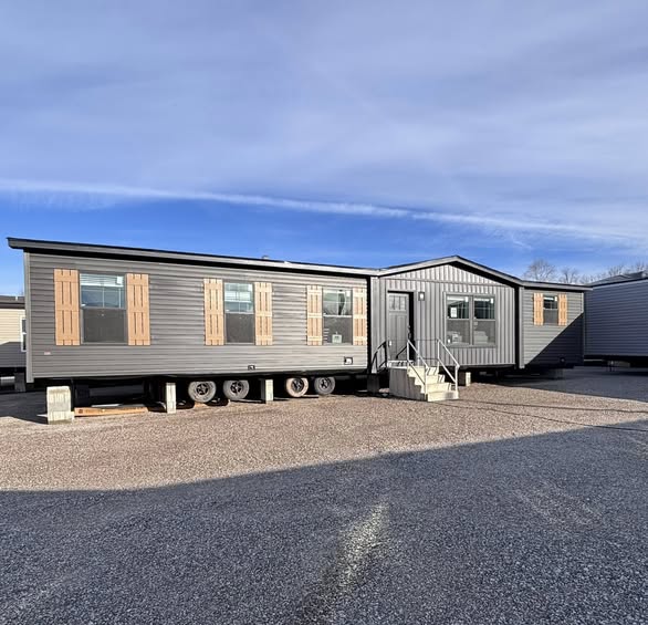 This extensive gallery features a variety of luxury housing models, including modern farmhouse manufactured homes, park models, and spacious modular residences. The exteriors showcase diverse high-end finishes, from classic white board-and-batten siding with dark pillars to charcoal-grey horizontal siding accented by natural wood shutters. Many models include architectural details like gabled front porches, dormer windows, and durable dark roofing.