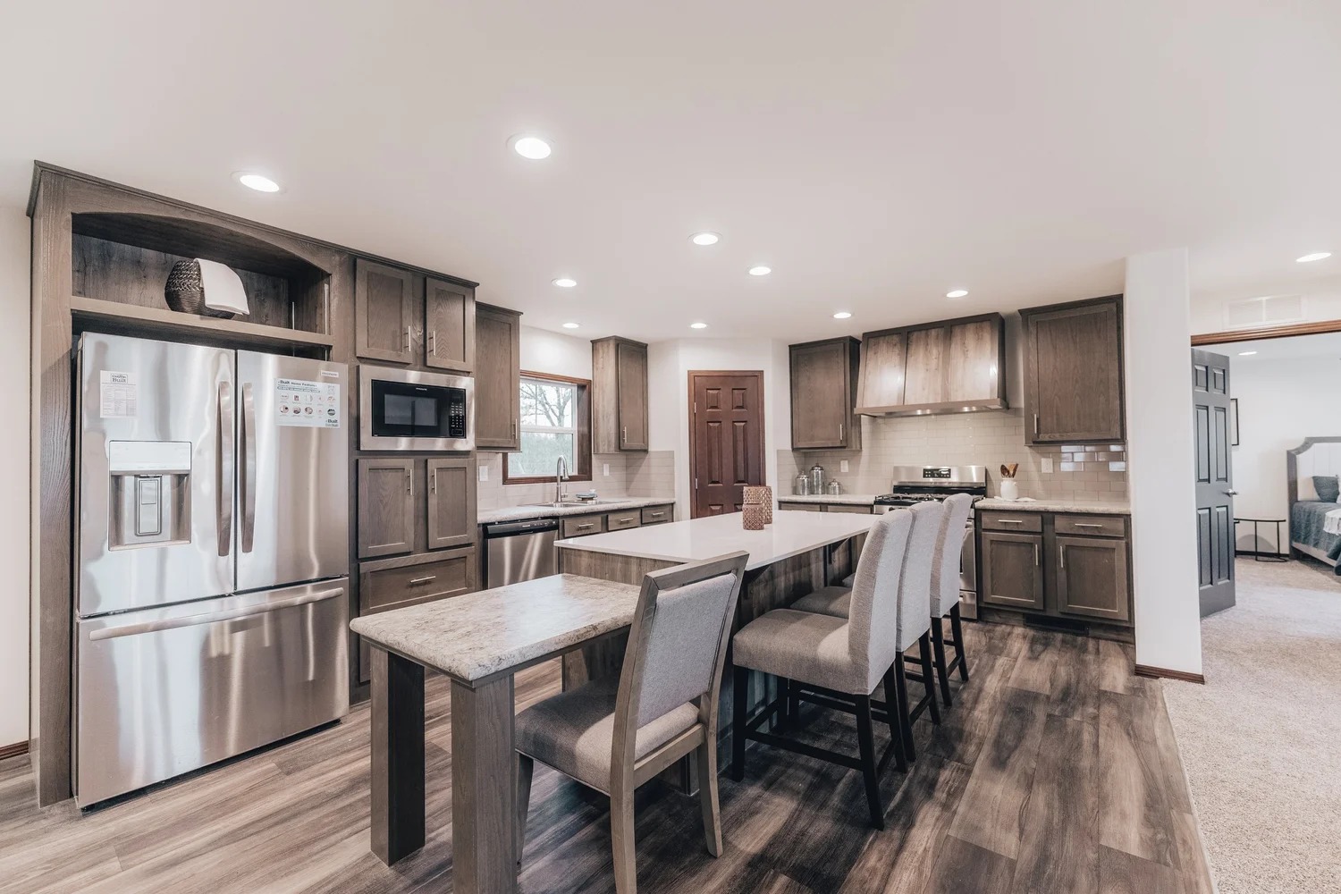 Spacious kitchen with modern design, featuring dark wood cabinets, stainless steel appliances, and a large island with seating. Bright, elegant, and inviting.