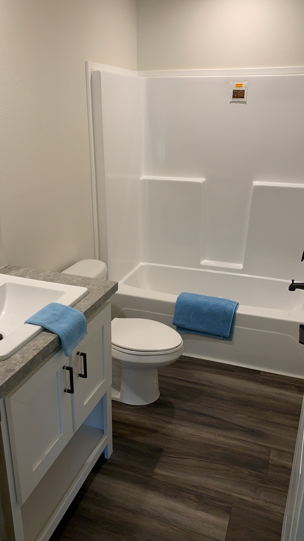 Comprehensive showcase of luxury manufactured and modular homes featuring navy blue and white farmhouse exteriors, 819 SQ FT floor plans, and modern interiors with quartz waterfall islands, hidden arched pantries, industrial corrugated metal accents, stone fireplaces, and vaulted tiny home lofts.