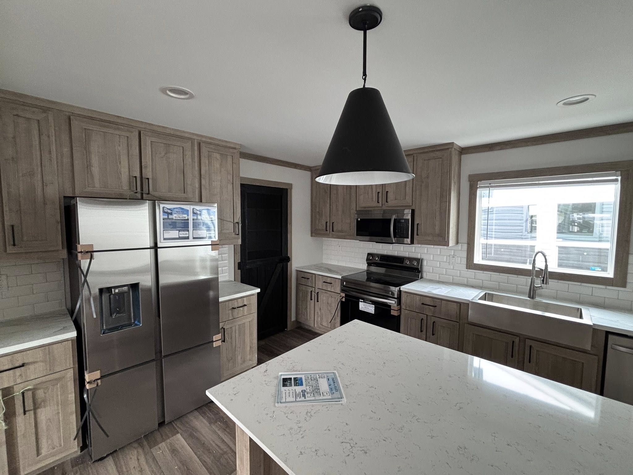 This extensive collection highlights the "Boujee XL" series of luxury tiny homes, park models, and manufactured homes, showcasing a sophisticated modern farmhouse aesthetic both inside and out. Exterior designs feature high-contrast color schemes, such as white or cream board-and-batten siding paired with charcoal gables, spacious gabled front porches with black or white support pillars, and durable metal roofs. The interior living areas emphasize open-concept luxury with vaulted ceilings, exposed wood beams, crisp white shiplap walls, and wide-plank wood-look flooring. Gourmet kitchens are equipped with premium finishes, including cabinetry in natural wood, white, or black tones, marble-patterned or distressed wood countertops, stainless steel farmhouse sinks, and large center islands with pendant lighting. Additional functional features include integrated lofted sleeping areas, industrial-style ceiling fans, transom windows for maximum natural light, built-in breakfast booths, and carpeted bedrooms designed for comfort.