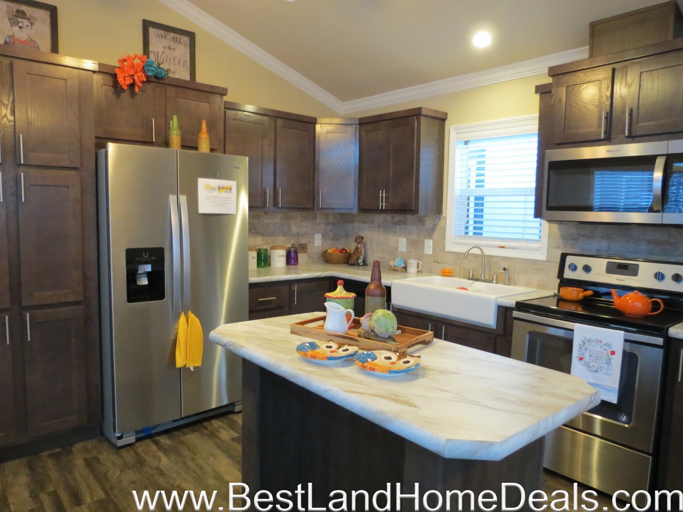 Modern kitchen with dark wood cabinets, stainless steel appliances, and a marble island. Bright decor accents and a cozy, welcoming atmosphere.