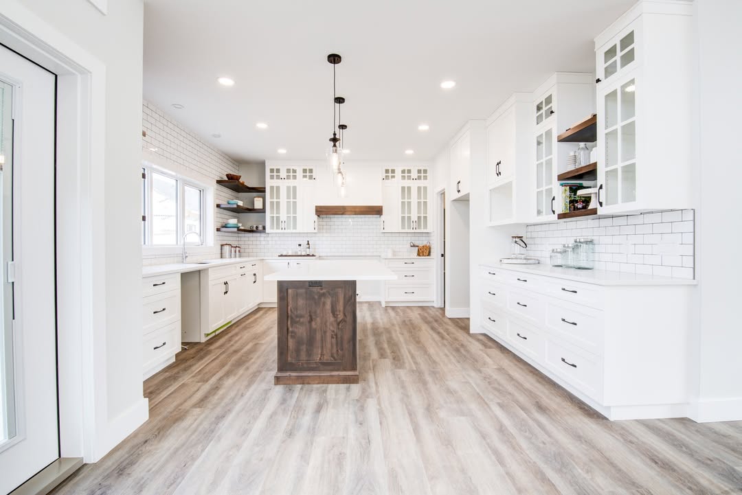 Bright, modern kitchen with white cabinets, a wooden island, and subway tile backsplash. Natural light streams through large windows, creating an inviting atmosphere.