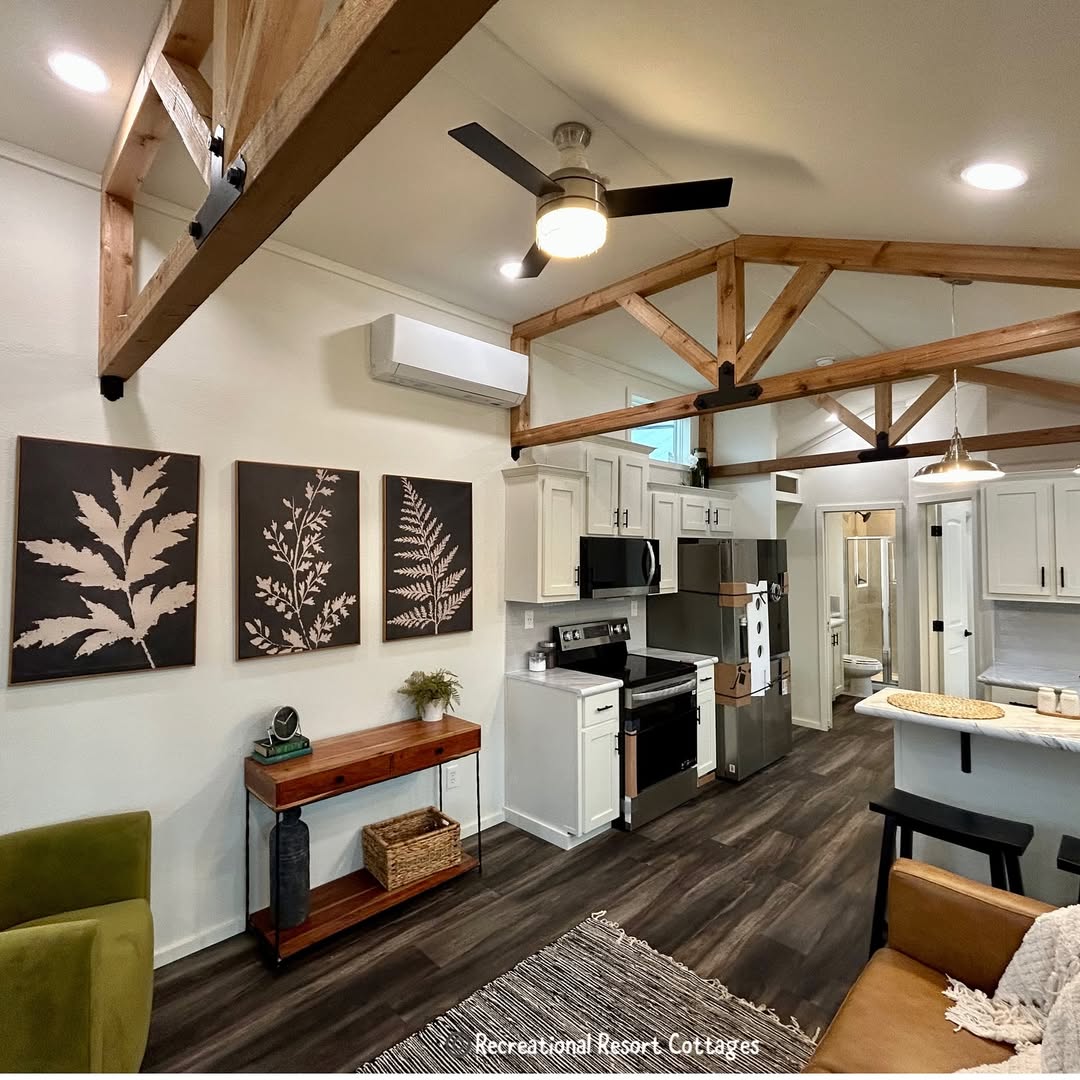 Interior of a cozy cottage with exposed wooden beams, a modern kitchen, and botanical artwork. Warm lighting and natural tones create a welcoming ambiance.
