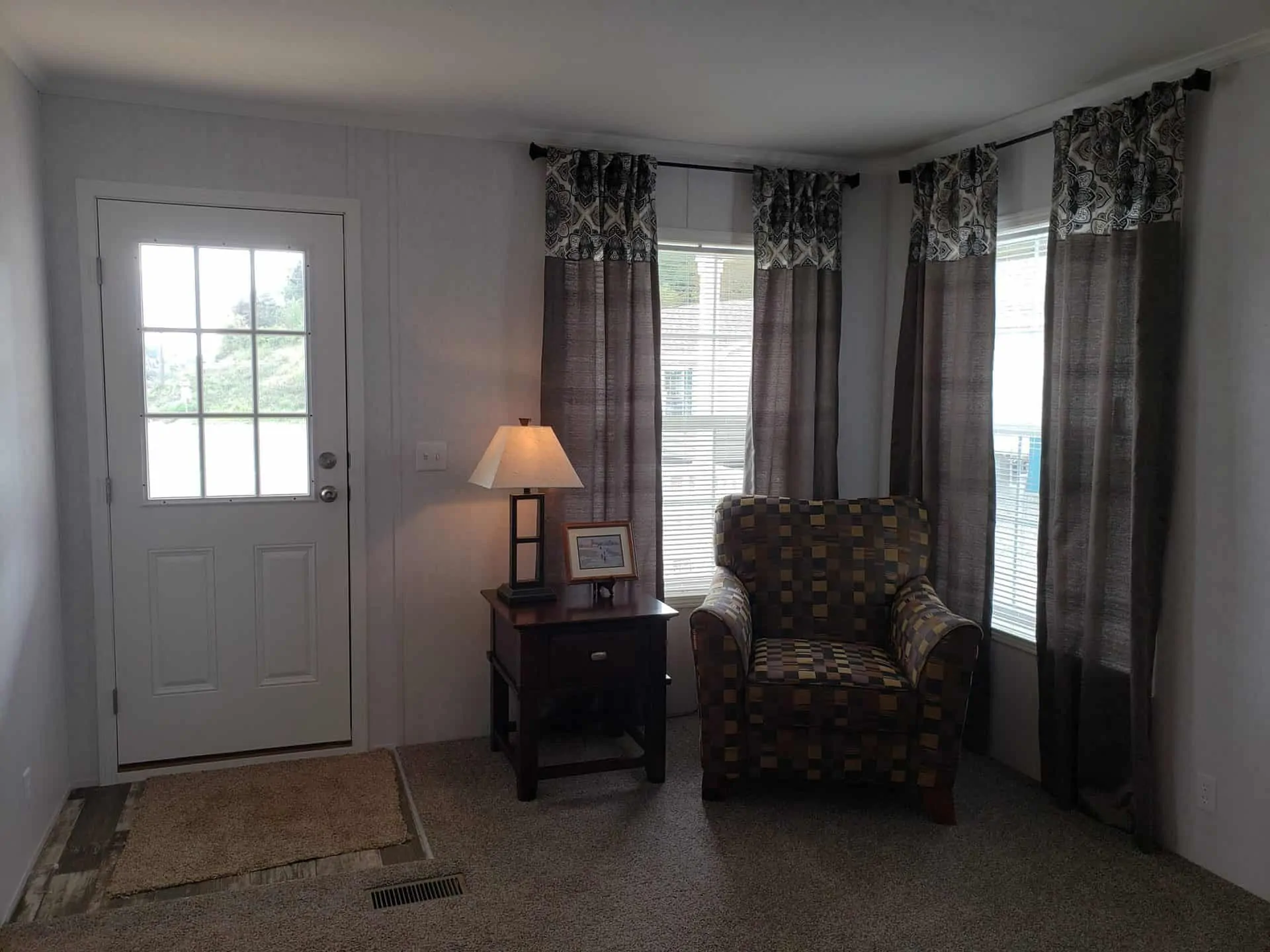 Luxury residential showcase featuring the expansive "The Boujee XL" manufactured home floor plan alongside a diverse collection of modern tiny homes and park models. Exterior architectural highlights include classic white board-and-batten farmhouses with grand pillared front porches and black metal railings, as well as a striking dark charcoal park model featuring a copper-tone metal roof, cedar wood accents, and a wrap-around elevated wooden deck. Interior design elements emphasize a "modern boujee" aesthetic with high-fidelity finishes. Open-concept living areas boast vaulted ceilings with rustic dark wood beams, white shiplap accent walls, and integrated electric fireplaces with custom mantels. Gourmet kitchens feature oversized islands in statement colors like teal, charcoal, and classic white, paired with marble-look waterfall countertops, farmhouse-style cabinetry, and professional-grade stainless steel appliances. Space-efficient luxury is highlighted through lofted sleeping quarters with black metal balustrades, custom built-in shelving, and cozy integrated breakfast nooks. Spa-inspired bathrooms include walk-in tile showers with black matte hardware, freestanding soaking tubs with marble-look surrounds, and double vanities with LED-mirrored lighting. This collection represents the pinnacle of premium manufactured living, offering versatile 4-to-5 bedroom layouts designed for high-end comfort and modern style.