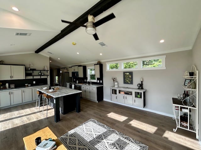 Spacious, modern kitchen with black and white decor, high ceilings, and an island with bar stools. Sunlight streams through high windows, creating a warm atmosphere.