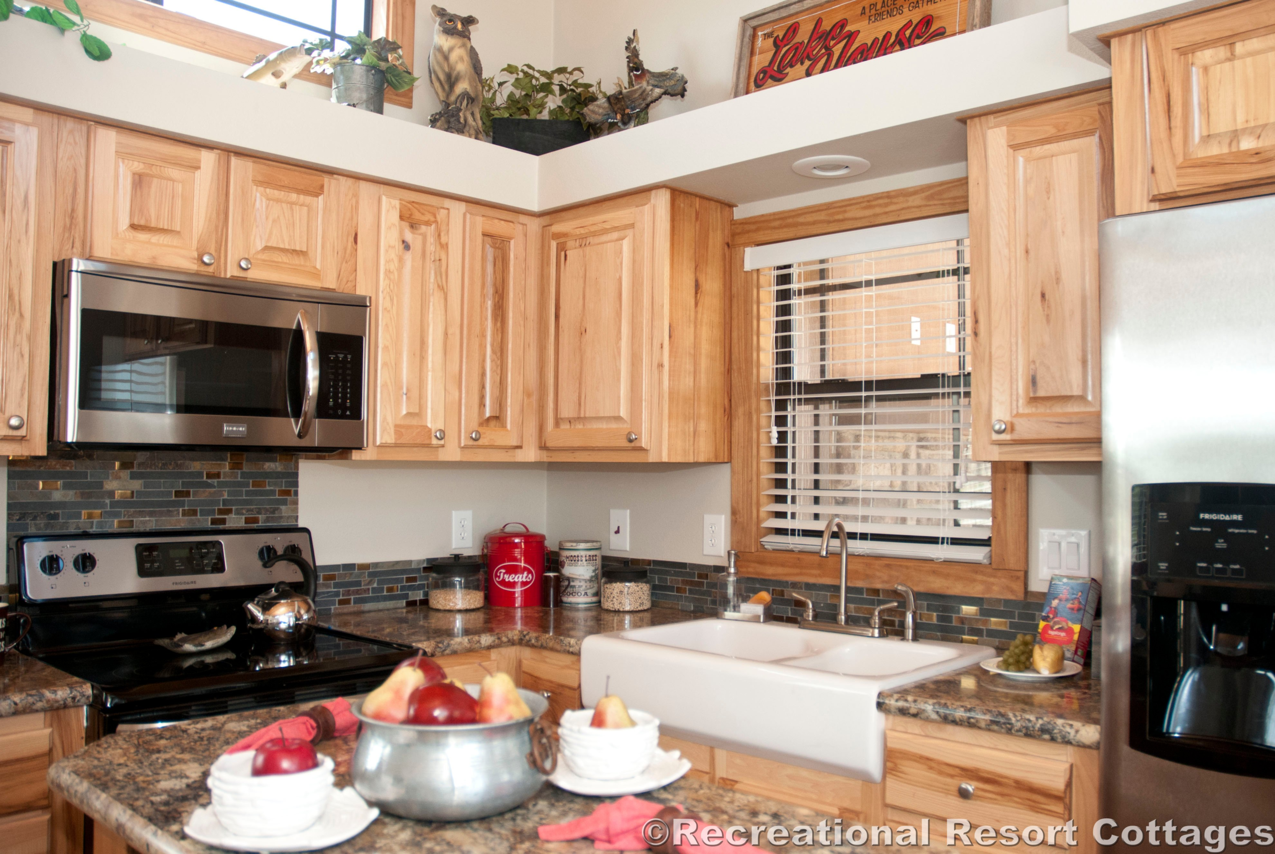 Cozy kitchen with wooden cabinets, stainless steel appliances, and a farmhouse sink. A bowl of fruit on the counter adds warmth and color.