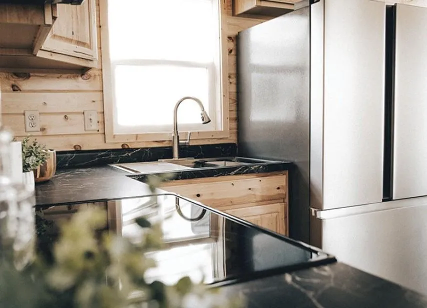 To help you optimize your website for search engines, here is the comprehensive Ultra-Level SEO Alt Text for your collection of luxury manufactured homes, park models, and tiny homes—featuring the "The Boujee XL" aesthetic.

Ultra-Level SEO Alt Text
Luxury housing showcase featuring the expansive "The Boujee XL" floor plan alongside a premium collection of modern tiny homes and park models. Exterior designs highlight a range of architectural styles, from classic white board-and-batten farmhouses with grand pillared porches and black metal railings to striking dark charcoal and cedar-toned models with copper metal roofing and wrap-around wooden decks.

Interior highlights focus on high-fidelity finishes and open-concept living. Living areas feature vaulted ceilings with rustic dark wood beams, white shiplap accent walls, and integrated electric fireplaces with custom mantels. Gourmet kitchens are a focal point, boasting oversized islands in statement colors like teal and charcoal, paired with marble-look waterfall countertops or dark stone surfaces, farmhouse cabinetry, and professional-grade stainless steel appliances.

The collection includes space-efficient luxury features such as lofted sleeping quarters with black metal balustrades, custom built-in shelving, and cozy breakfast nooks. Spa-inspired primary bathrooms include walk-in tile showers with black matte hardware, freestanding soaking tubs, and double vanities with LED-mirrored lighting. This gallery represents the pinnacle of modern manufactured living, offering versatile 4-to-5 bedroom layouts perfect for a high-end, "boujee" lifestyle.