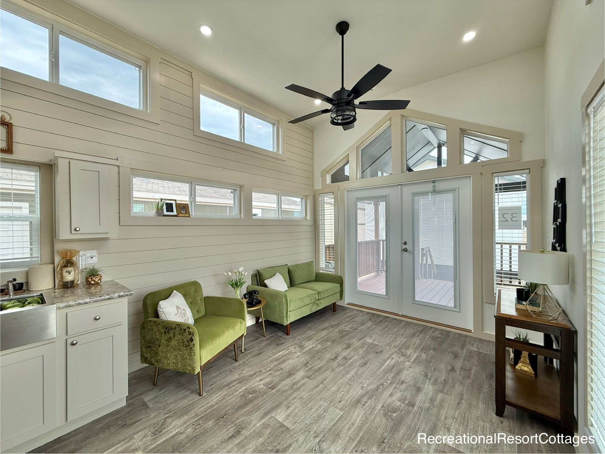 Luxurious modern tiny house on wheels featuring a striking deep navy blue exterior with rustic wood trim and a spacious screened-in front porch, contrasted by a warm and inviting interior with wood-paneled walls, high-end stainless steel kitchen appliances, a cozy living area with a plush beige sofa, and a functional loft bedroom, perfectly showcasing innovative small-space living and contemporary mobile home architecture for maximum SEO ranking.