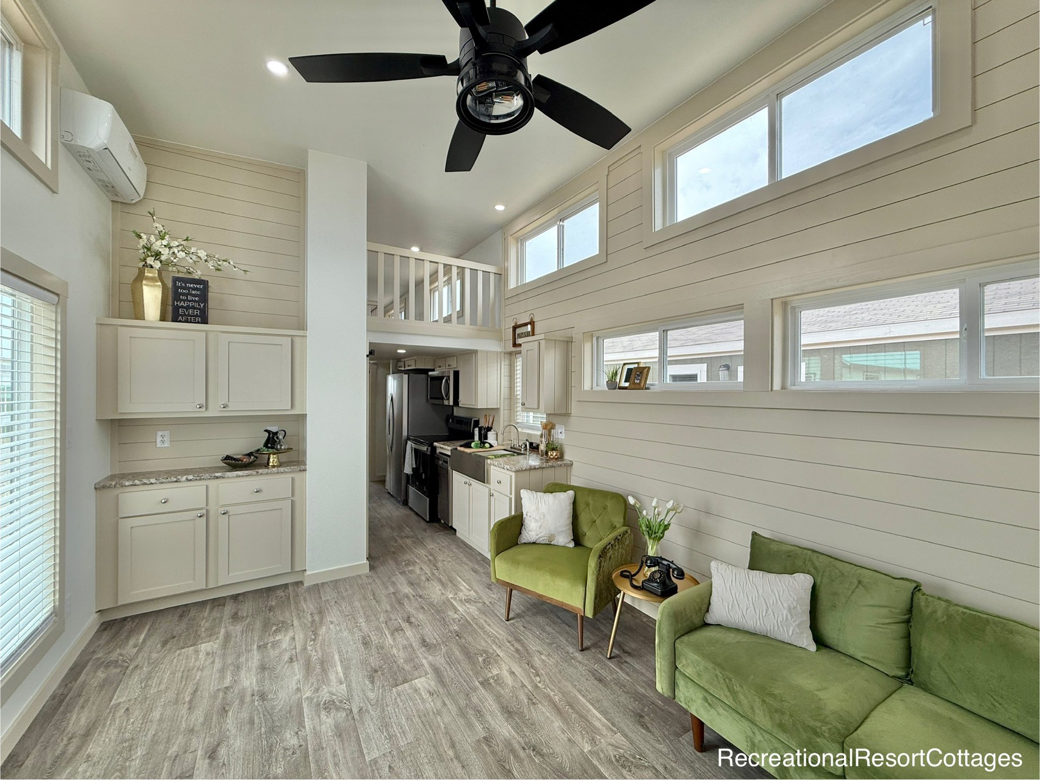 Modern luxury tiny house on wheels featuring a deep navy blue exterior with rustic wood trim and a spacious front porch, paired with a cozy interior view showing a high-end kitchen with stainless steel appliances, a comfortable living area with a beige sofa, and a loft bedroom, highlighting efficient small-space living and modern architectural design for maximum SEO impact.