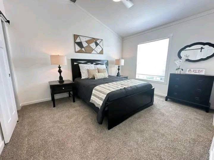A modern bedroom with a dark wood bed, striped bedding, and matching nightstands. Soft lamps emit warm light, creating a cozy, inviting atmosphere.