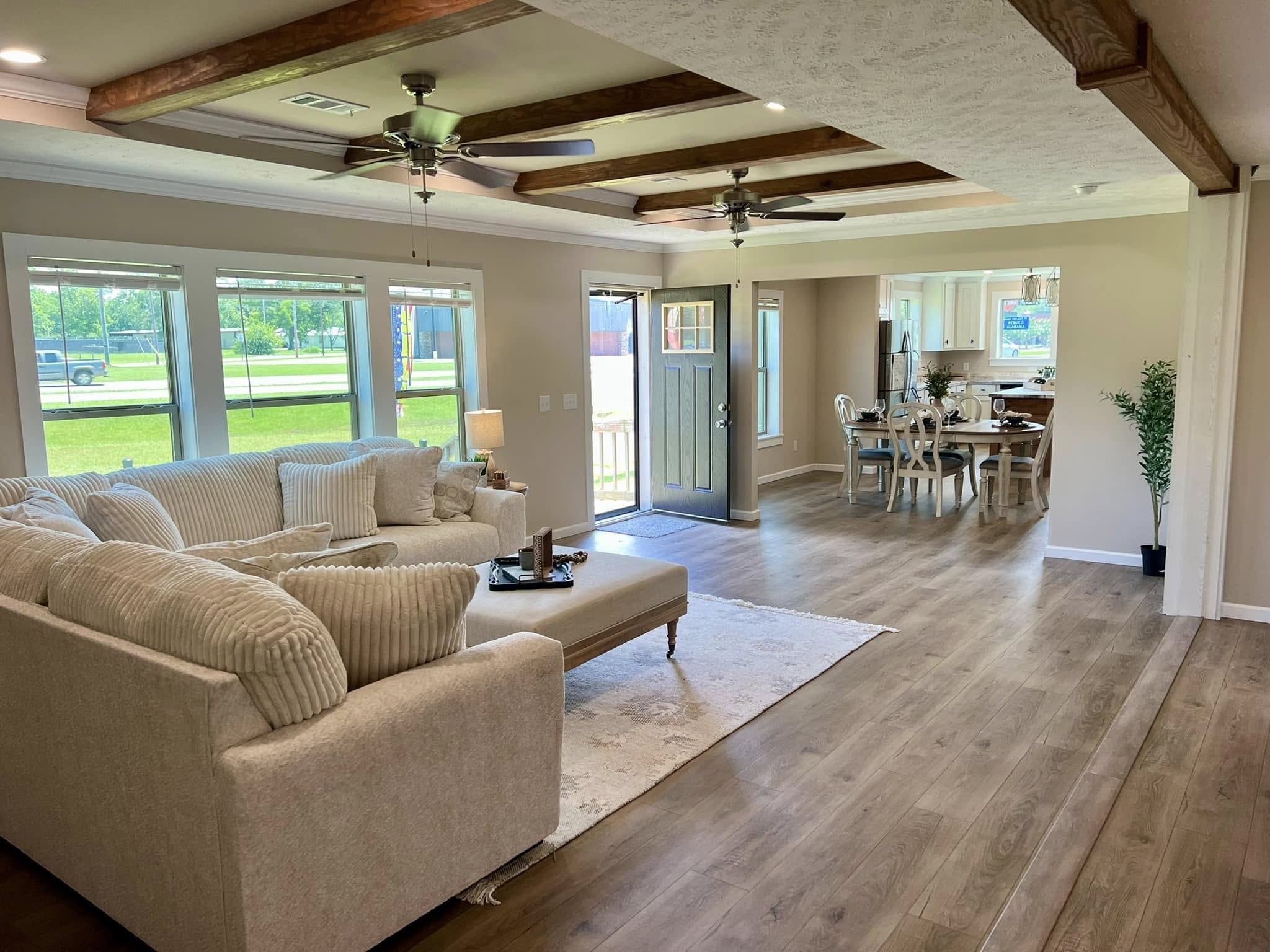 SEO-optimized alt text for a luxury manufactured home interior, featuring a spacious gourmet kitchen with white shaker cabinetry, a large kitchen island with a reclaimed wood-style countertop, and a rustic red brick backsplash; the open-concept floor plan showcases premium finishes like stainless steel appliances, modern pendant lighting, and durable wood-look flooring that flows into a bright dining area and living room, perfectly capturing the essence of high-end mobile living, contemporary farmhouse decor, and innovative modular home design for maximum search engine ranking and visibility.