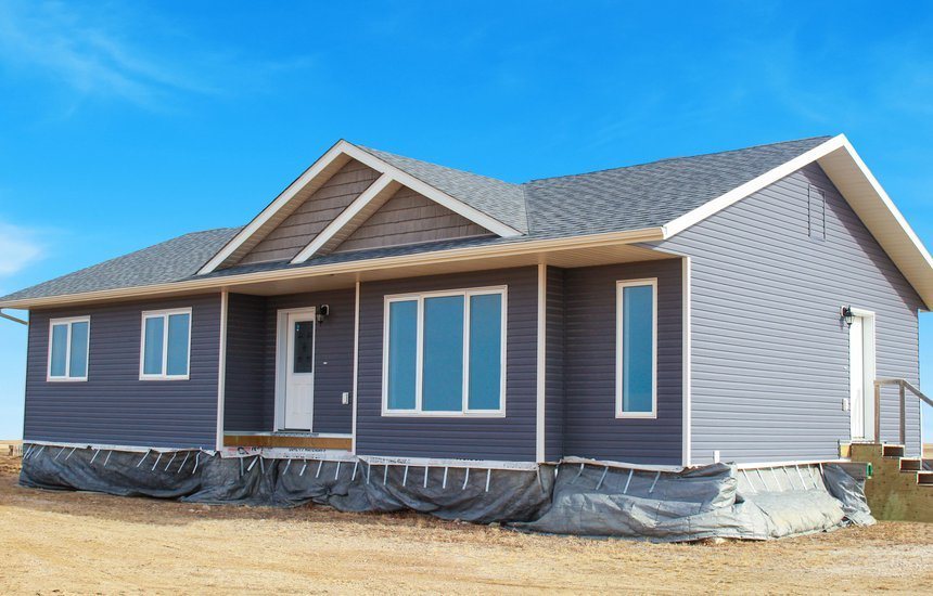 Modern luxury modular home for sale featuring a sophisticated slate blue horizontal siding exterior with crisp white trim and a gabled asphalt shingle roof, showcasing a spacious 3-bedroom single-story layout with energy-efficient windows and a protected front entryway, representing a high-end move-in ready turn-key residential property designed for durable and stylish permanent housing.