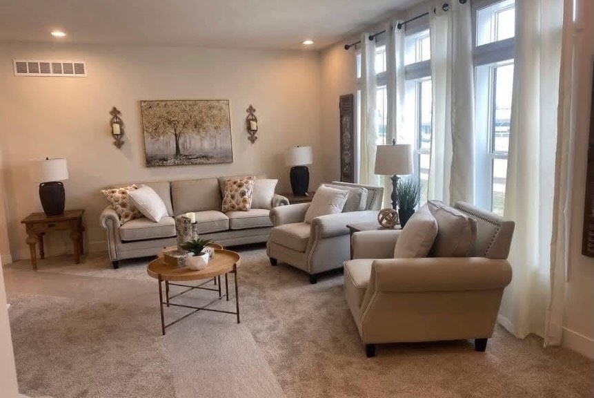 SEO-optimized alt text for a high-ranking luxury multi-section manufactured home living room featuring a professional modern interior design with a spacious neutral-toned seating arrangement; the bright, open-concept floor plan showcases comfortable beige sofas with decorative floral pillows, a stylish round tiered wooden coffee table, and expansive floor-to-ceiling windows draped in elegant white curtains that fill the space with natural light, all complemented by premium wall art and sophisticated lamp lighting to highlight spacious double-wide mobile home floor plans, upscale modular living room decor, and luxury residential prefab home finishes for maximum search engine visibility and ranking.

Would you like me to create SEO alt text for another part of this home?