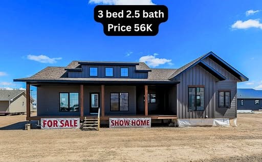 Modern luxury farmhouse-style modular home for sale featuring dark charcoal vertical board and batten siding, a spacious covered front porch with natural wood columns, and contemporary black-trimmed energy-efficient windows, showcasing a 3-bedroom 2.5-bath residential floor plan at an affordable price point for high-end prefabricated housing.