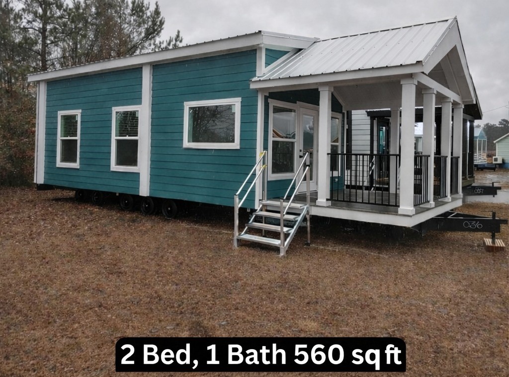 Gemini said Exterior of a 560 square foot, 2-bedroom, 1-bath tiny home featuring vibrant teal blue horizontal siding, crisp white trim, and a spacious covered front porch with white columns and black railings, showcasing a modern prefabricated cottage design with a durable silver metal roof and energy-efficient windows for affordable luxury living.