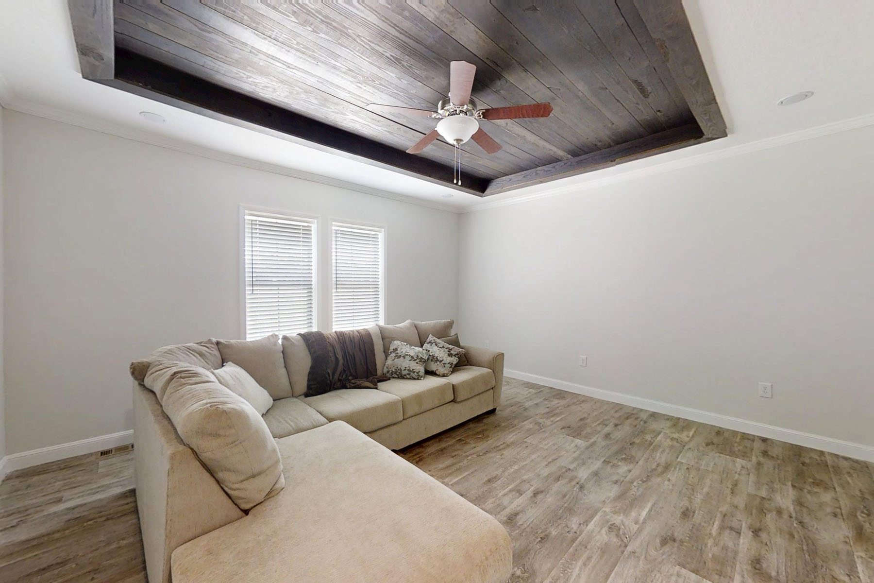 Modern living room featuring a custom floor-to-ceiling stacked stone fireplace with a dark wood timber mantle, a black electric fireplace insert, and a raised grey flagstone hearth, flanked by built-in white shaker-style bookshelves and cabinets on light oak hardwood flooring, creating a perfect example of transitional interior design and cozy home renovation inspiration.