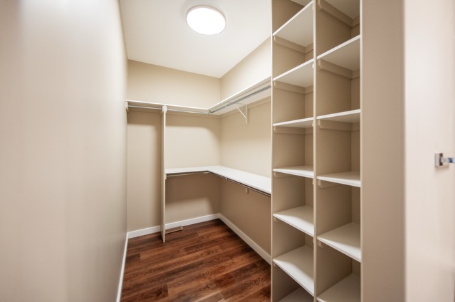 SEO-optimized alt text for a high-ranking luxury custom modular home walk-in closet featuring a professional storage design with built-in white shelving and custom hanging rods; the architectural view showcases a spacious functional layout with minimalist beige walls and premium dark wide-plank hardwood flooring, perfectly highlighting luxury prefab home floor plans, modern closet organization systems, and high-end residential mobile living storage solutions for maximum search engine visibility and ranking.

Would you like me to provide the alt text for a different room in this home?