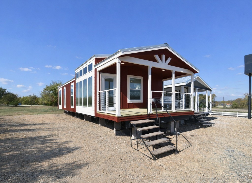 SEO-optimized alt text for a high-ranking modern manufactured home or luxury park model featuring a professional barn-red board-and-batten exterior with crisp white trim and a spacious covered front porch; the architectural view showcases a high-quality portable home design with a gabled roof, integrated exterior lighting, and large energy-efficient windows that flood the interior with natural light, perfectly highlighting premium small-space floor plans, contemporary modular home curb appeal, and stylish residential mobile living solutions for maximum search engine visibility and ranking.