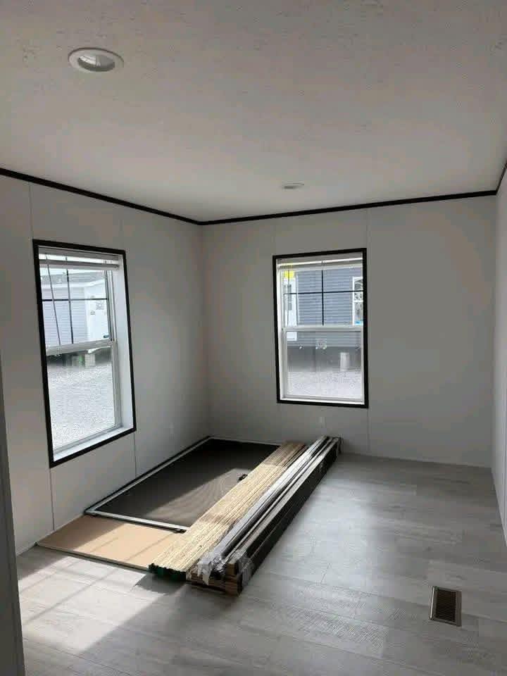 Modern luxury 4-bedroom manufactured home featuring a spacious open-concept living room with a large grey sectional sofa, an elegant gourmet kitchen with a white marble-patterned island, and a spa-like master bathroom with a deep soaking tub and double vanity, all showcasing high-end finishes like wood-look vinyl flooring and contemporary fixtures for a sophisticated move-in ready turn-key residential design.