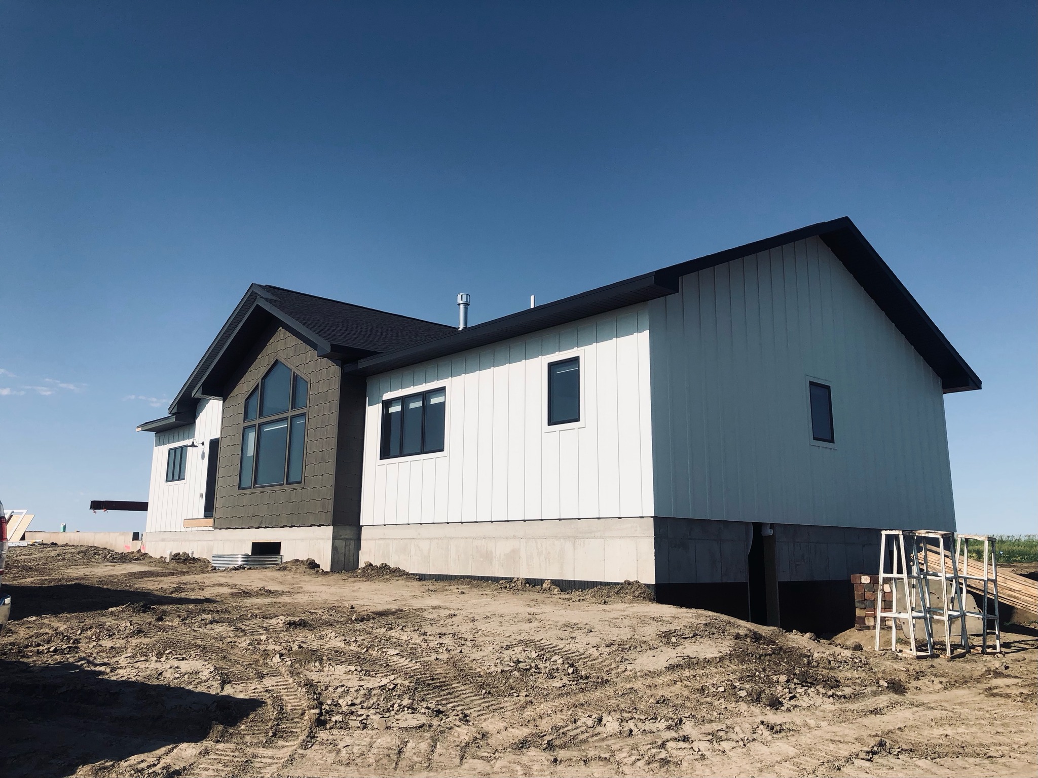 SEO-optimized alt text for a high-ranking modern luxury modular home featuring a professional white board-and-batten exterior with a sophisticated dark gray gabled accent wall and large architectural windows; the exterior view showcases a high-quality prefab residence built on a solid concrete foundation with a sleek dark roofline, perfectly highlighting premium manufactured home curb appeal, contemporary residential floor plans, and upscale durable construction for maximum search engine visibility and ranking.